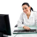 front view of smiling doctor working on computer on white backgr